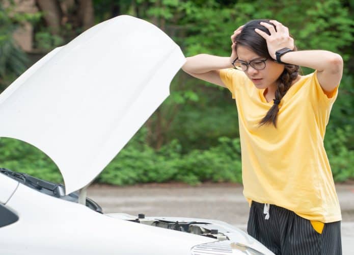 Jovem mulher estressada tendo problemas com a pane de seu carro na estrada e ela está esperando alguém que possa ajudá-la. Conceito de acidente de carro na estrada.