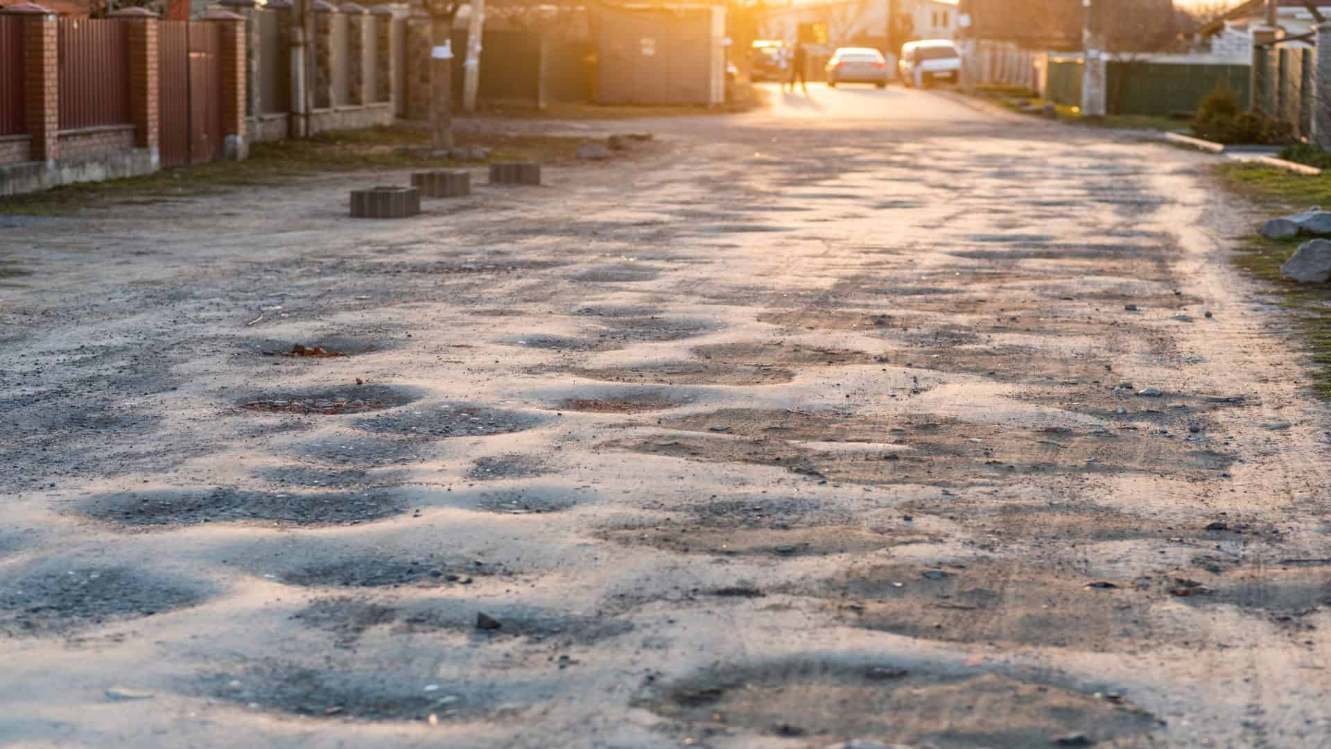 Conceito de má qualidade da estrada: antiga estrada de asfalto cheia de buracos e buracos que precisam de reparação