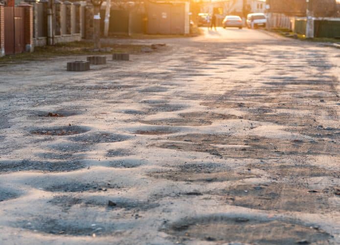 Conceito de má qualidade da estrada: antiga estrada de asfalto cheia de buracos e buracos que precisam de reparação
