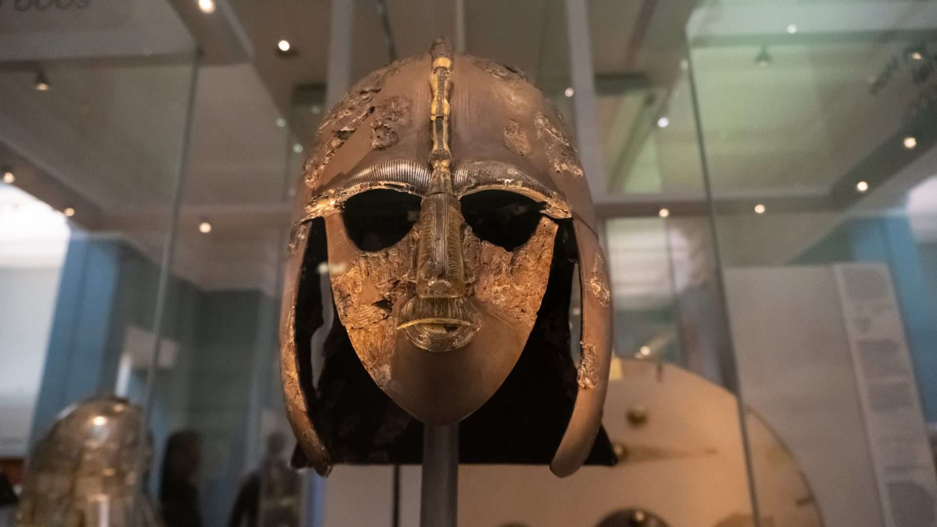 O capacete Sutton Hoo, um capacete anglo-saxão decorado encontrado durante uma escavação de 1939 no navio funerário Sutton Hoo. Em exposição atrás de um vidro.