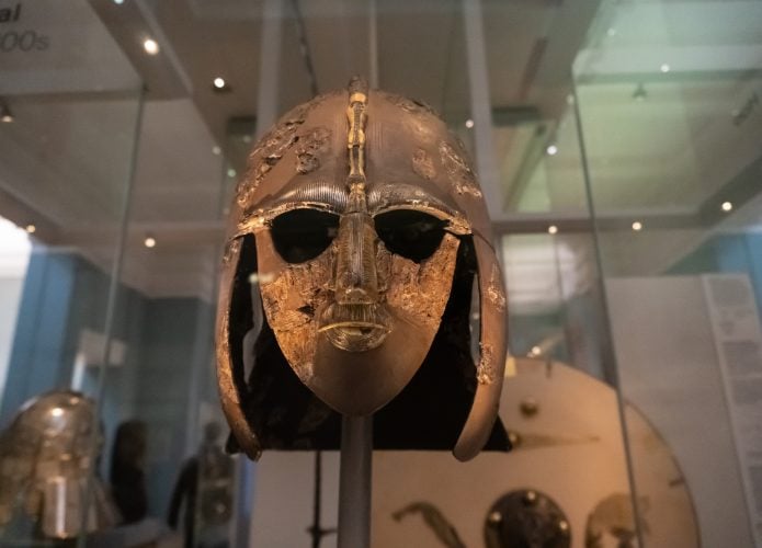 O capacete Sutton Hoo, um capacete anglo-saxão decorado encontrado durante uma escavação de 1939 no navio funerário Sutton Hoo. Em exposição atrás de um vidro.