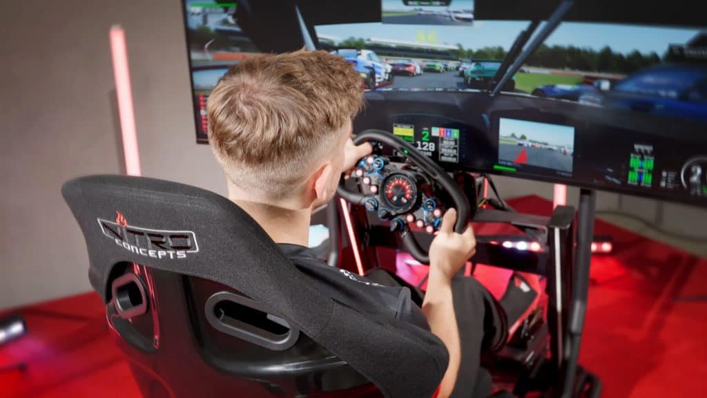 Detalhe, de trás, de um homem com as mãos no volante do simulador e jogando um game de corrida