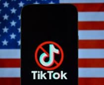 Logo do TikTok com um ícone de proibição por cima em um smartphone; atrás, a bandeira dos Estados Unidos