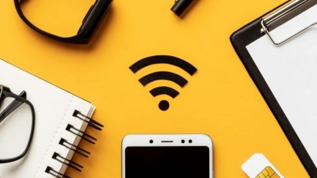 imagem com fundo amarelo, caderno, celular, tablet e um símbolo de wi-fi