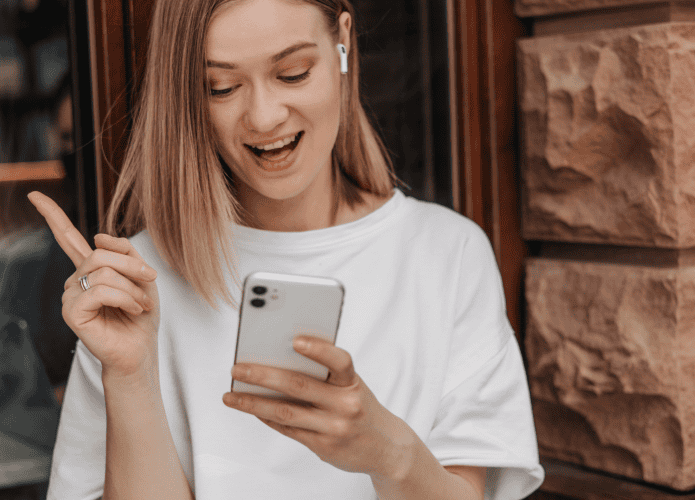 Mulher branca e loira segurando um celular