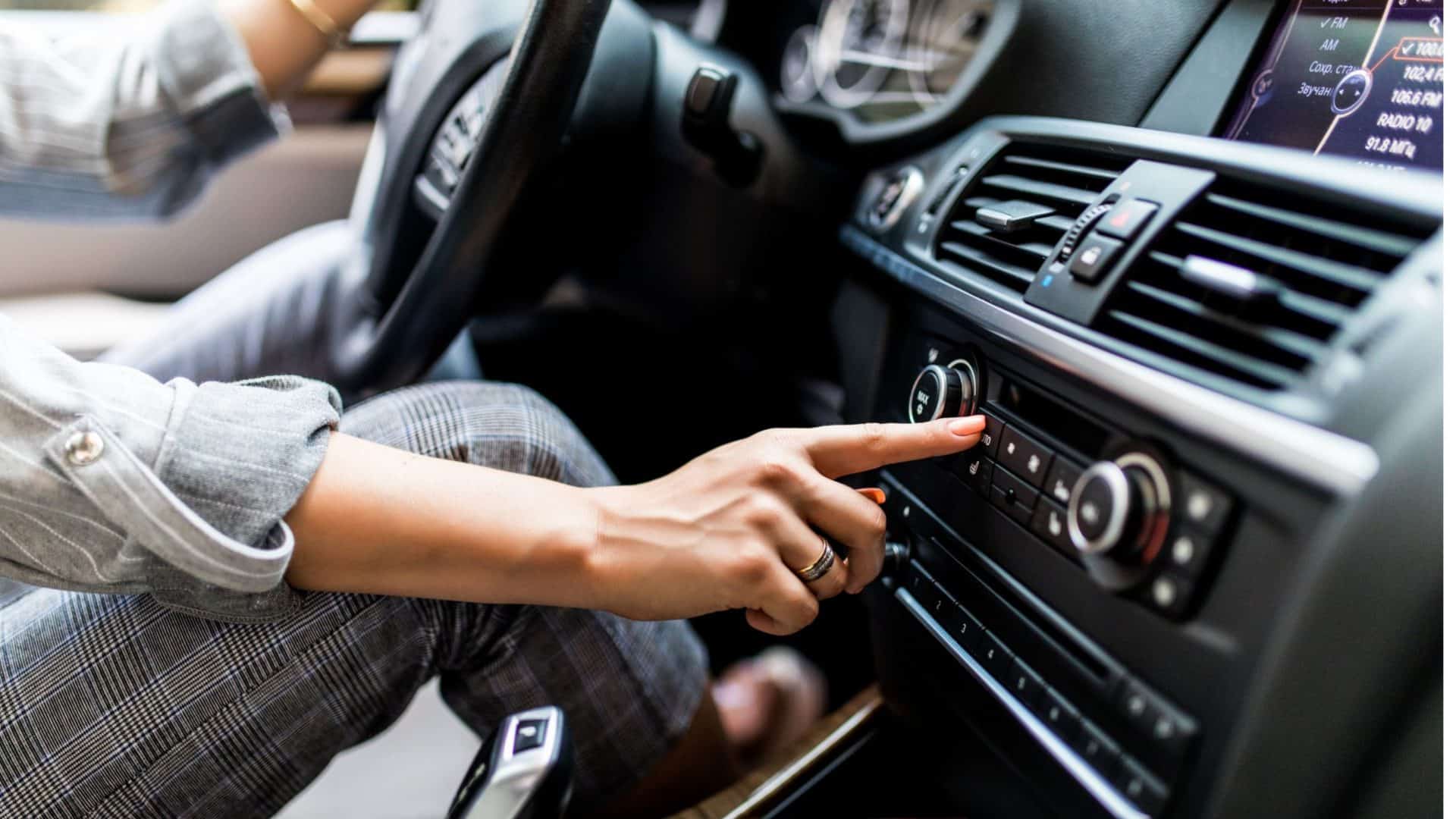 mulher aciona ar condicionado do veículo