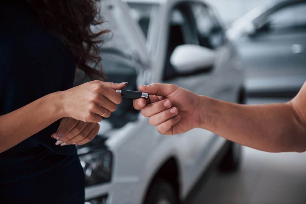 mulher entregando chave de carro para outra pessoa