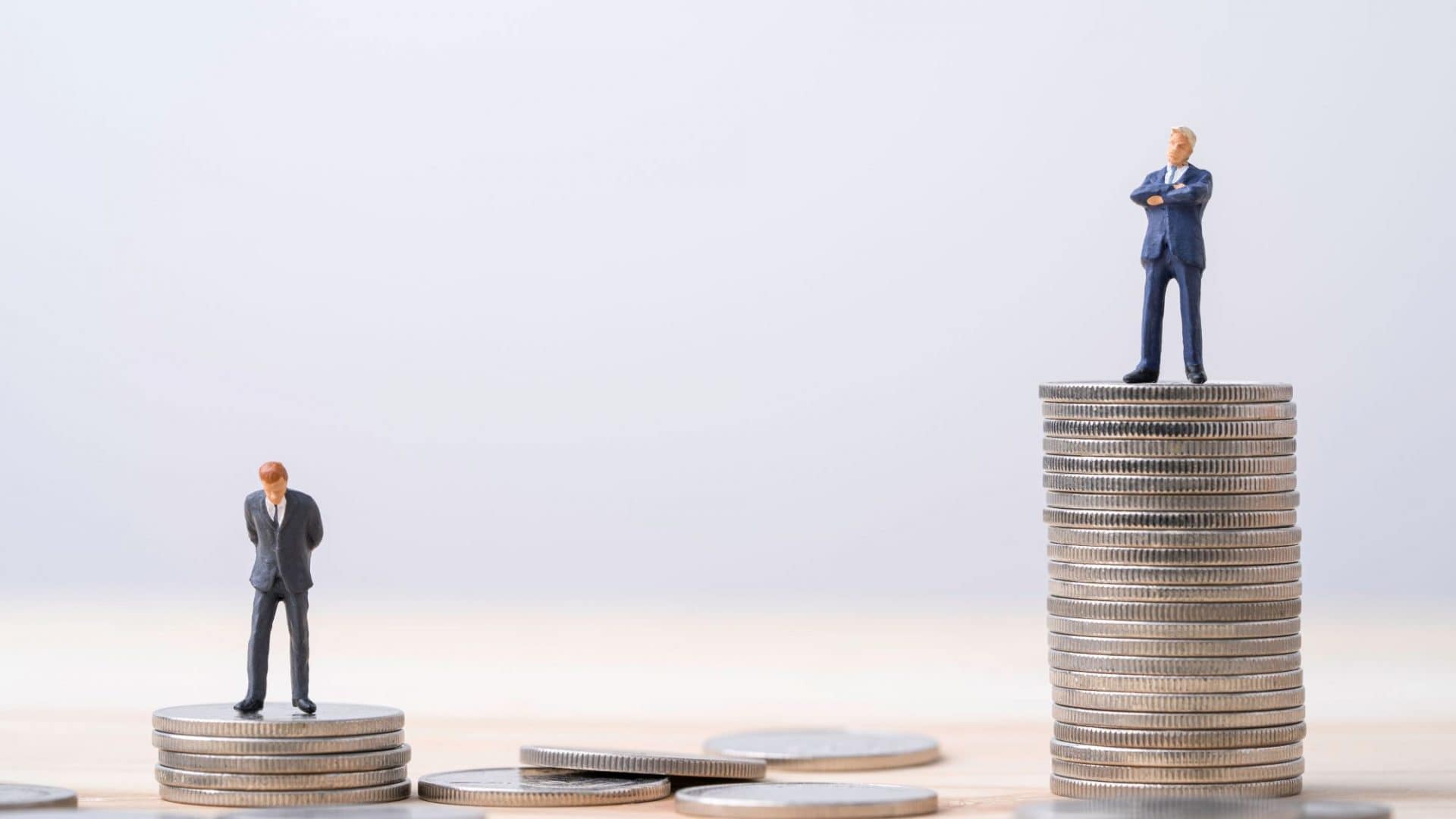 Dois montes de moedas, sendo que, o da direita, é maior; em cima de ambos, estão duas figuras masculinas