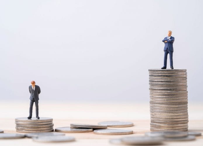 Dois montes de moedas, sendo que, o da direita, é maior; em cima de ambos, estão duas figuras masculinas