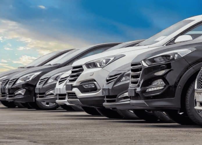 carros enfileirados em um pátio com céu ao fundo