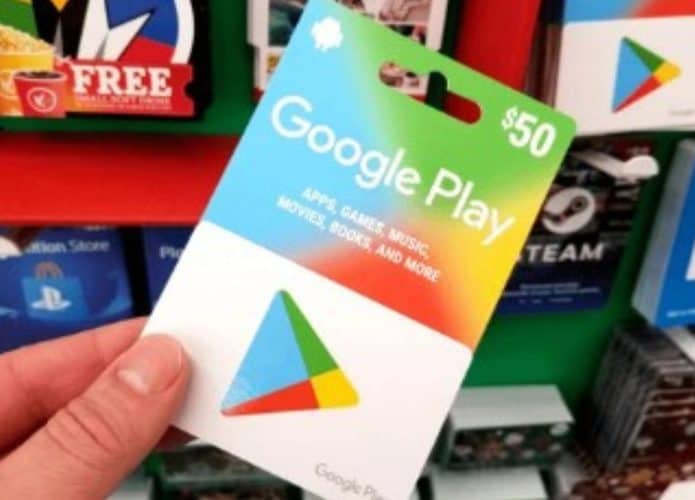 pessoa segurando um gift card google play com outros de outras empresas no fundo