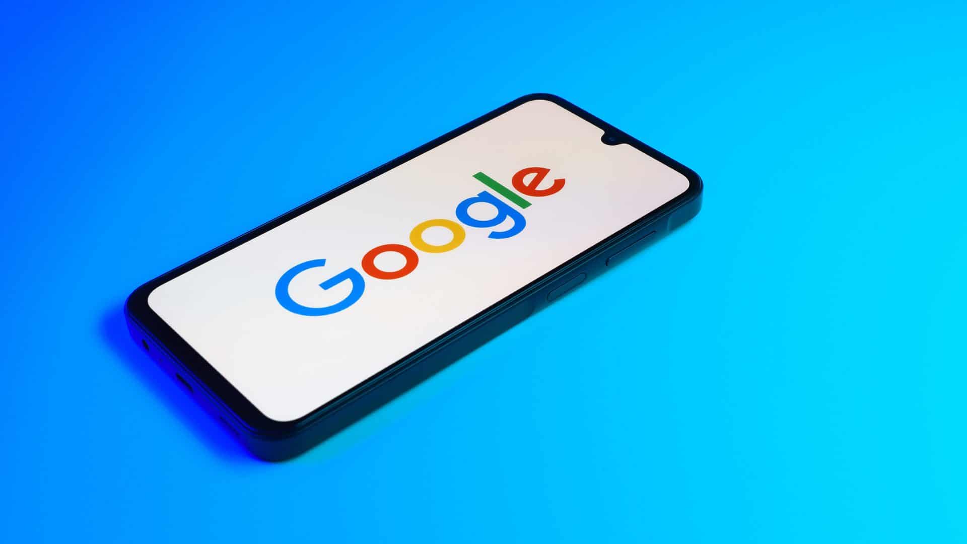 Logo do Google na tela de um smartphone que está em cima de uma superfície azul