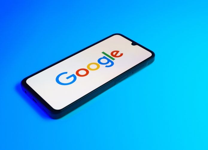 Logo do Google na tela de um smartphone que está em cima de uma superfície azul
