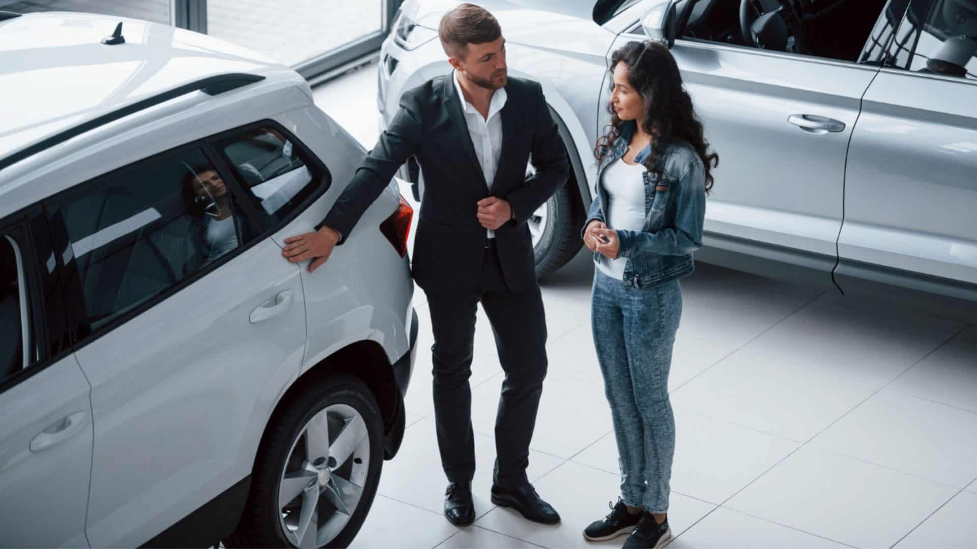 homem apresentando carro para uma muler