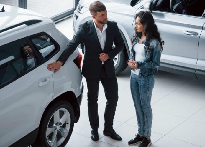 homem apresentando carro para uma muler