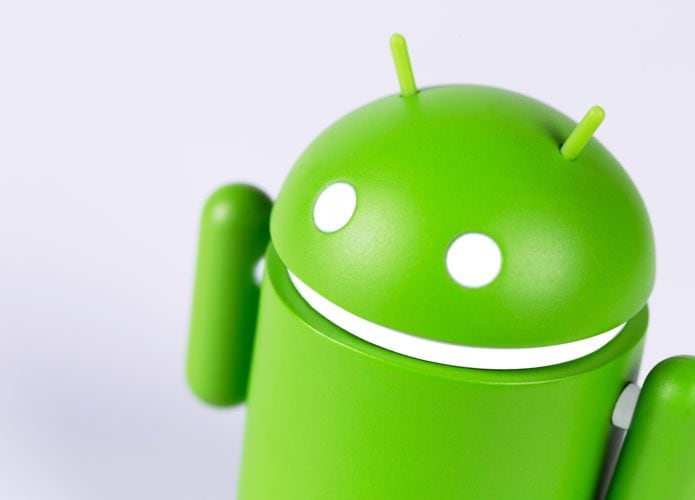 Robozinho do Android meio de lado e próximo à câmera em fundo branco