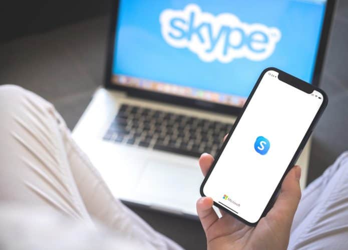 Mulher usando smartphone com aplicativo Skype.