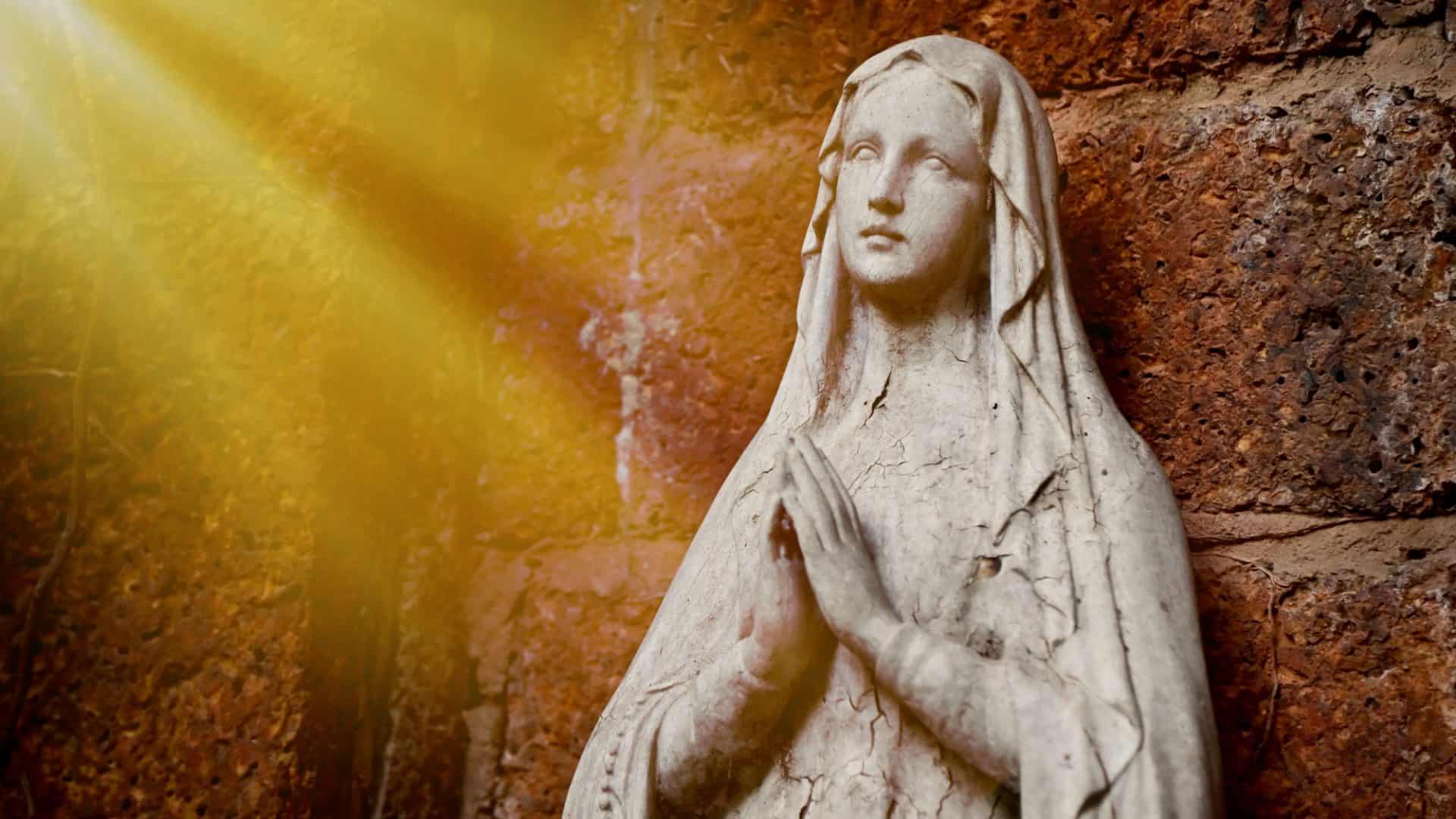 Estátua de Virgem Maria, vista com fundo natural em caverna rochosa