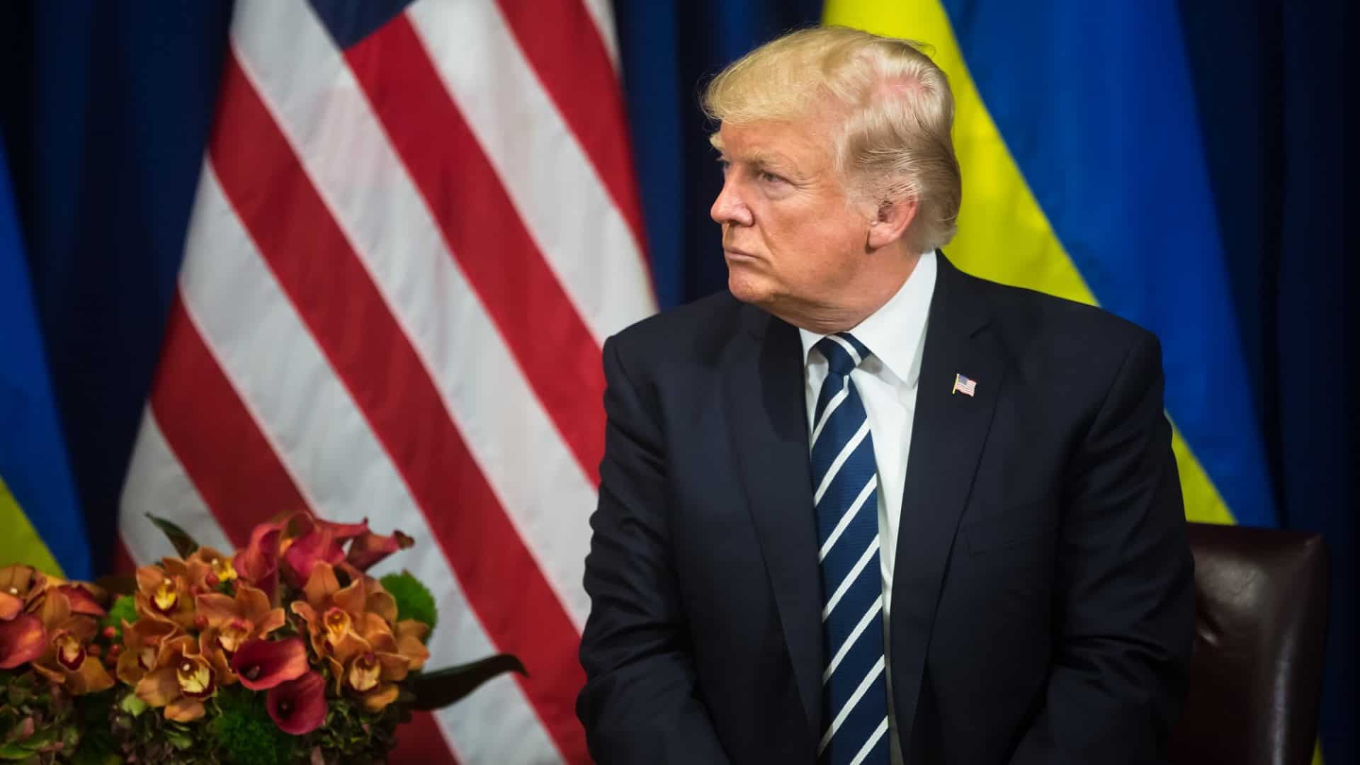donald trump em frente às bandeiras de estados unidos e ucrânia