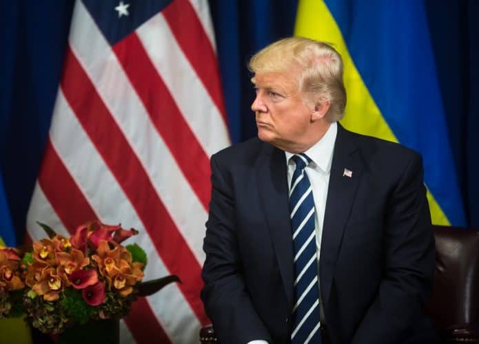 donald trump em frente às bandeiras de estados unidos e ucrânia