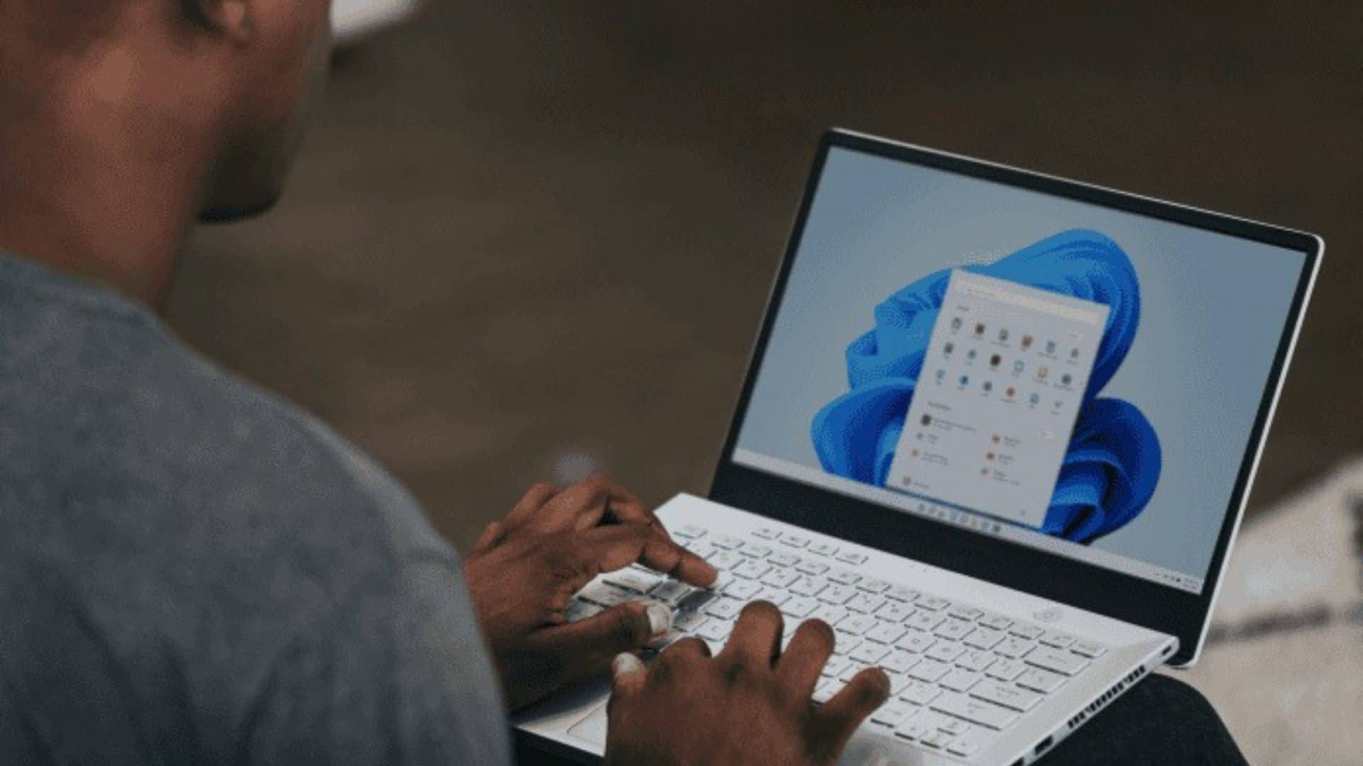 Homem mexendo em um notebook cujo sistema operacional é o Windows 11