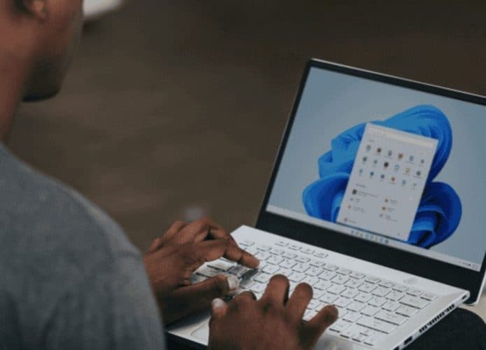 Homem mexendo em um notebook cujo sistema operacional é o Windows 11