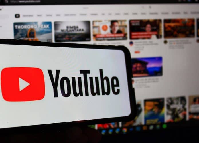 À frente, logo do YouTube em um smartphone; atrás, página do YouTube em um notebook