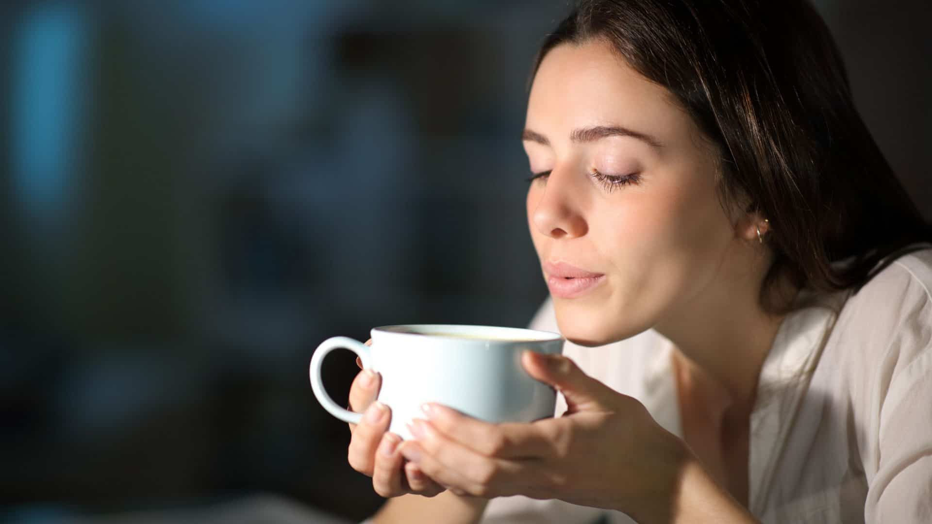 mulher assoprando uma xícara de café