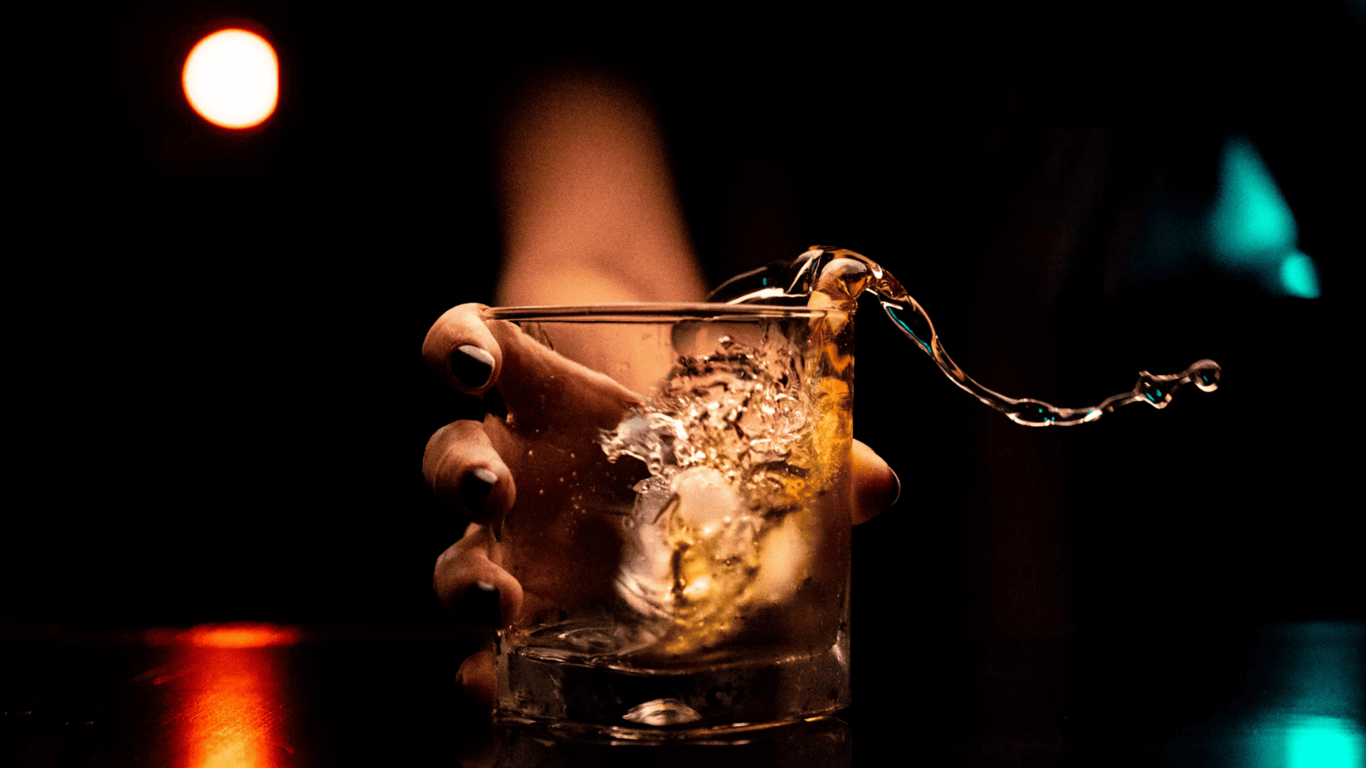 Pessoa segurando um copo vazando bebida alcoólica