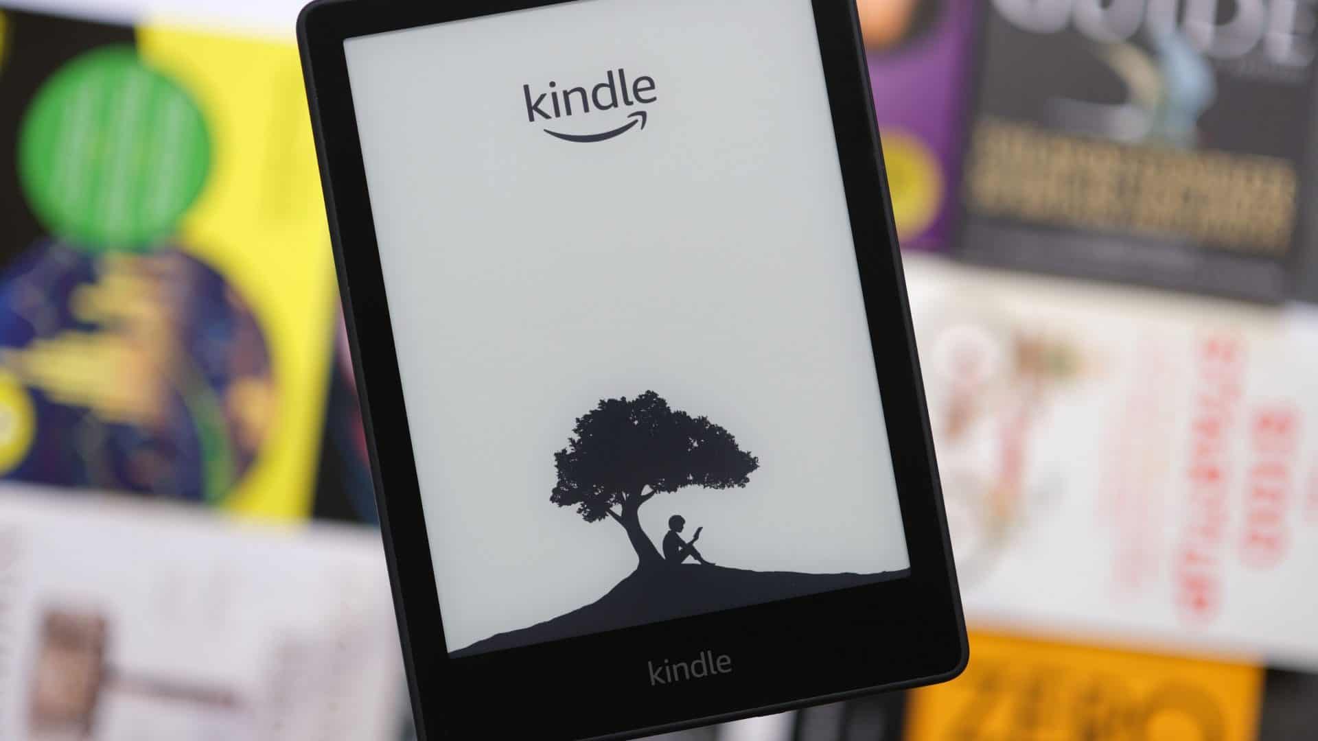 Close de um Kindle com livros desfocados ao fundo