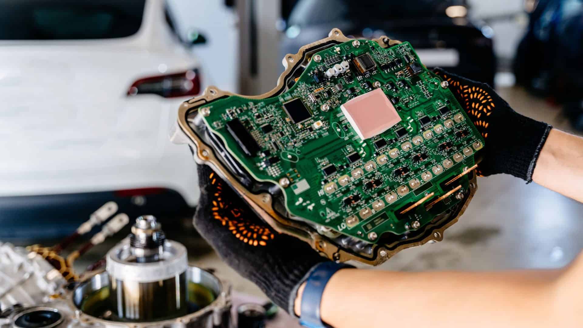 Pessoa segurando ECU de carro em oficina