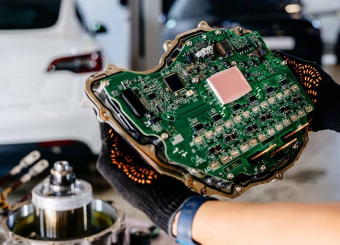 Pessoa segurando ECU de carro em oficina