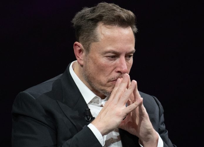 Elon Musk com as mãos na frente do rosto e expressão preocupada