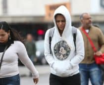Pessoas andando agasalhadas na rua em dia frio