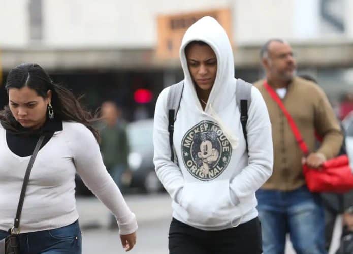 Pessoas andando agasalhadas na rua em dia frio
