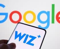 Pessoa segurando celular com logomarca da Wiz na tela colocado na frente de tela exibindo logomarca do Google