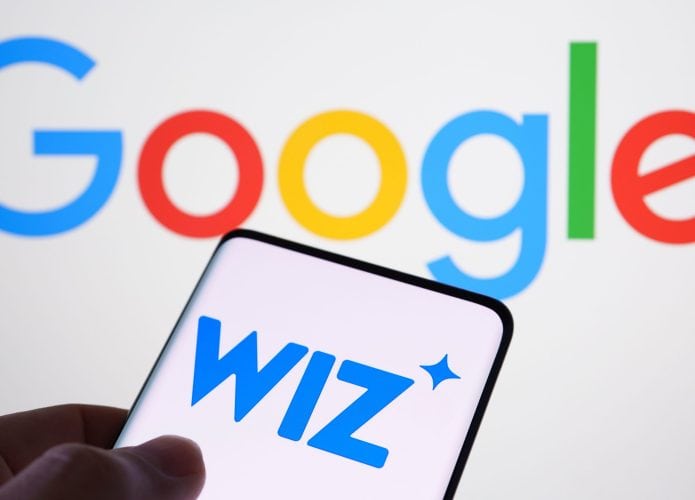 Pessoa segurando celular com logomarca da Wiz na tela colocado na frente de tela exibindo logomarca do Google
