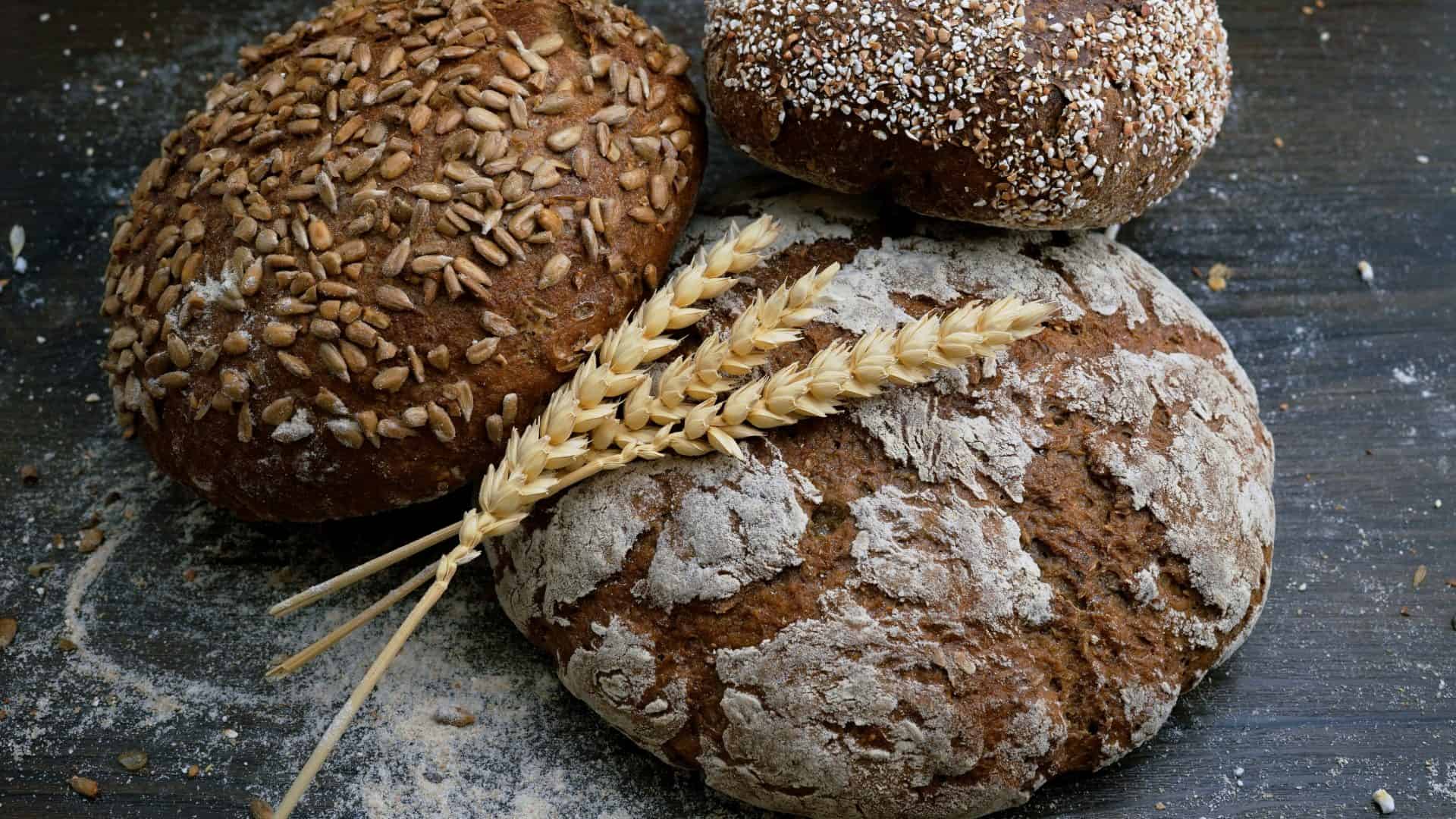 Três pães integrais decorados com dois galhos de trigo