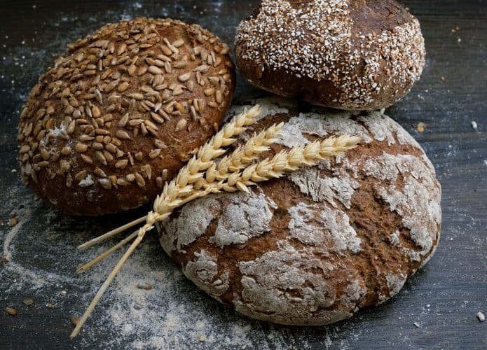 Três pães integrais decorados com dois galhos de trigo