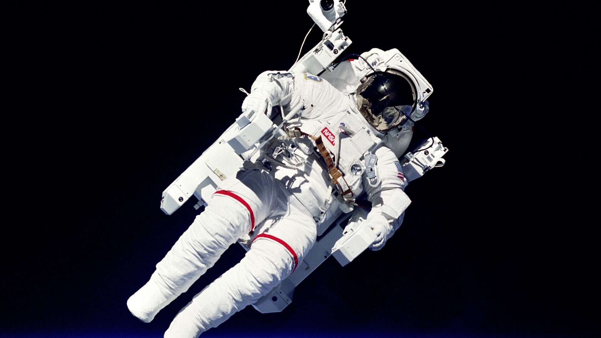 Bruce McCandless II Sobrevoando o planeta terra na primeira caminhada espacial sem cordas de retenção.