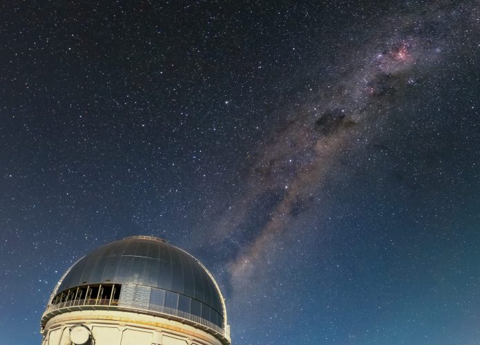 A Via Láctea brilhando acima do Telescópio Víctor M. Blanco de 4 metros (que foi usado na descoberta da galáxia) no CTIO - CTIO/NOIRLab/NSF/AURA/D. Munizaga