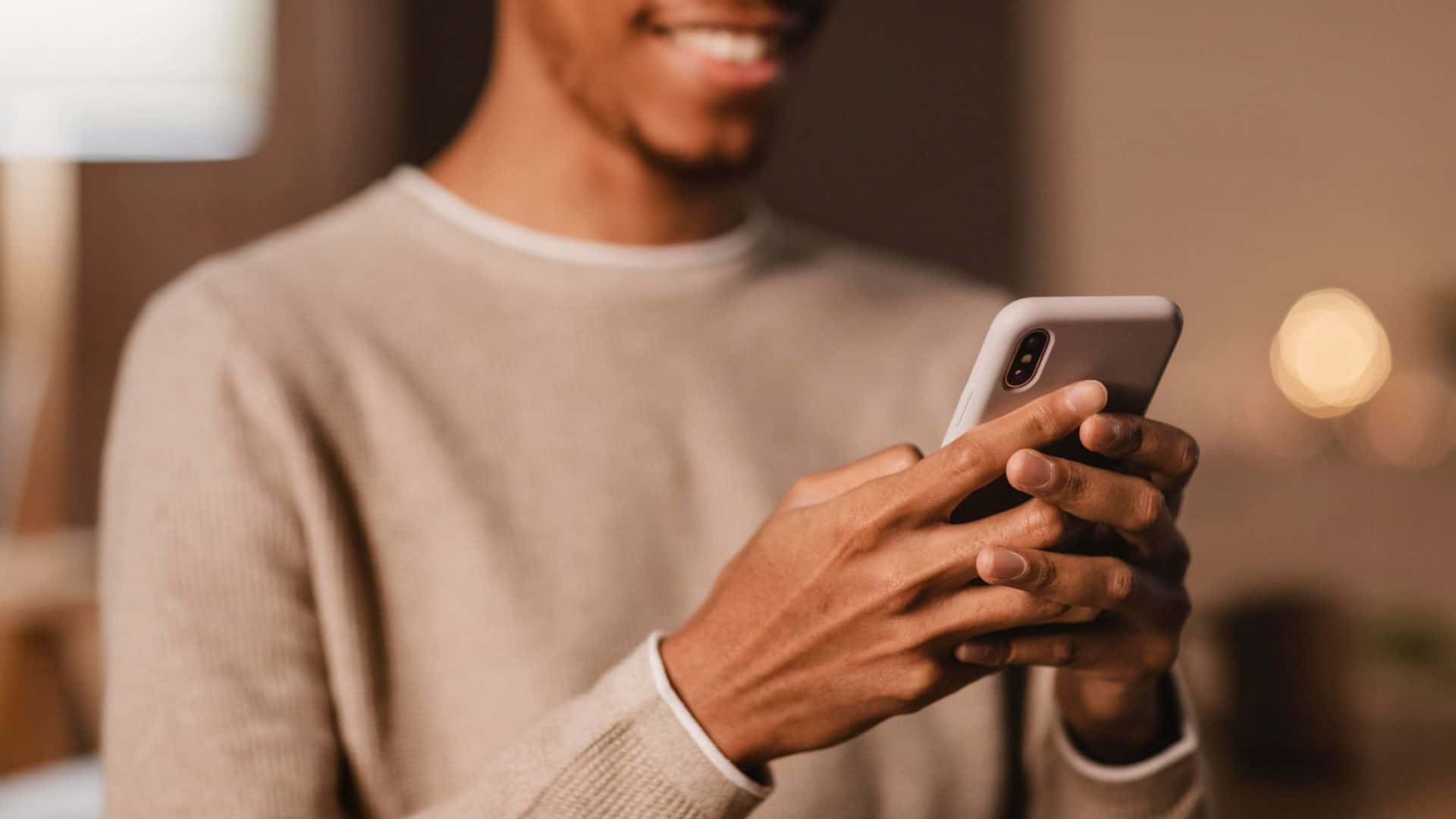 homem segurando o celular enquanto sorri