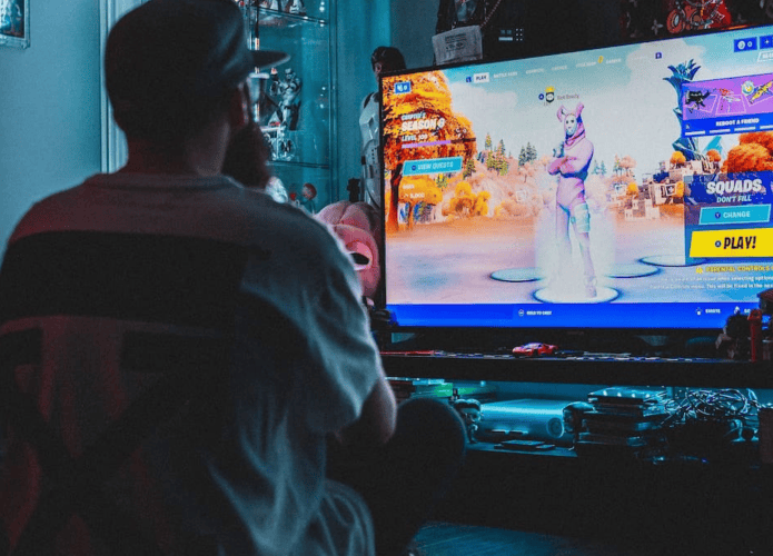 Pessoa jogando Fortnite em frente a televisão