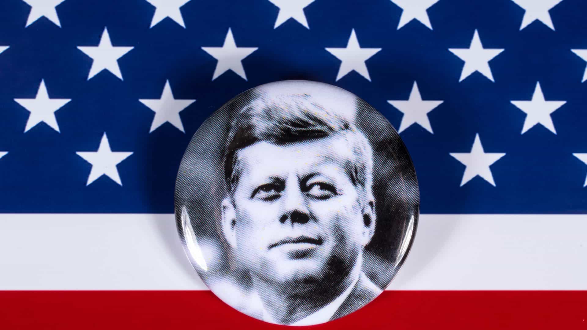 Foto de John F. Kennedy à frente de parte da bandeira dos EUA