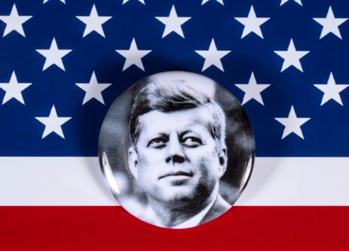 Foto de John F. Kennedy à frente de parte da bandeira dos EUA