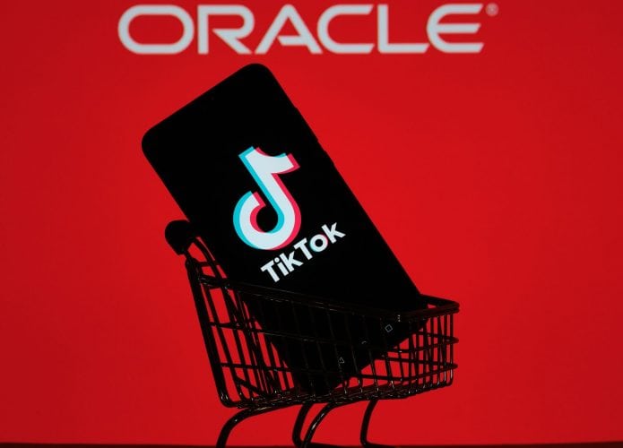 Ao fundo, logo da Oracle em uma tela vermelha; à frente, um smartphone em um mini-arrinho de compras com o logo do TikTok