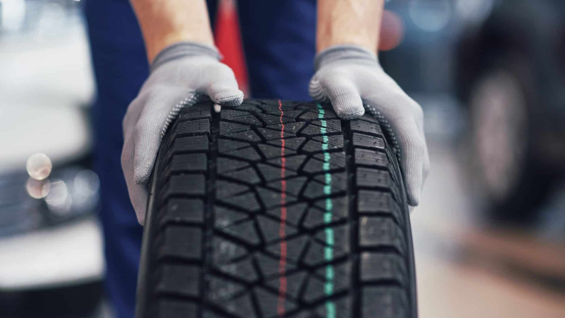 pessoa de luva segurando um pneu de carro