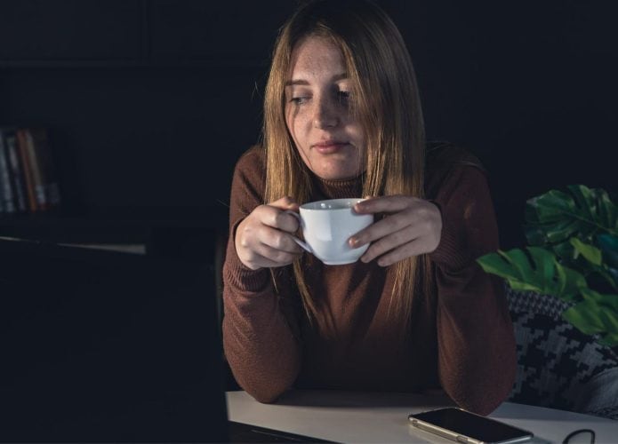 mulher com xícara de café em frente a um computador