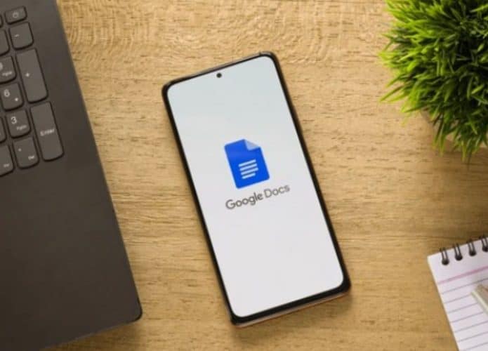 celular com google docs em uma mesa ao lado de um notebook
