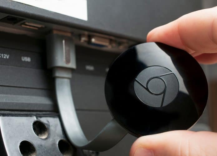 Homem mostra um dispositivo Google Chromecast conectado a uma TV